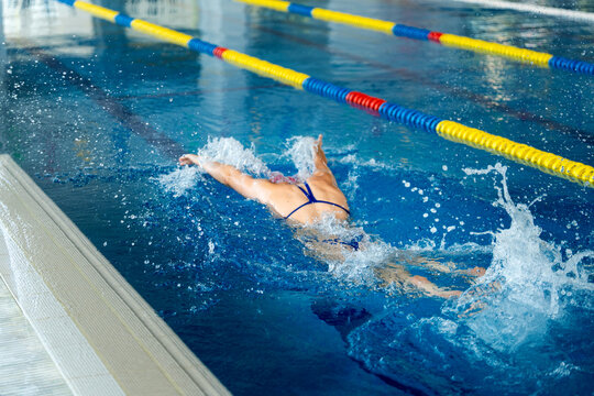 Female swimmer training butterfly stroke in pool, focusing on discipline and self-improvement