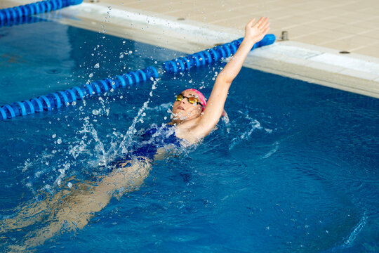 Female swimmer training backstroke in pool, representing sport, discipline and self-improvement