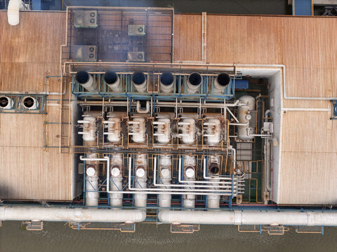 Aerial view of an industrial power plant facility featuring rows of chimneys, complex piping systems, and metallic rooftop structures in Santo Domingo, Distrito Nacional, Dominican Republic.
