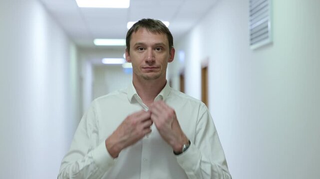 Successful male executive in a formal suit walking through a bright corporate hallway directly towards the camera.Split screen or sequence of a professional businessman walking back and forth in a con