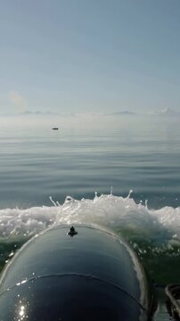 Vertical video: Surging bow tube after surge, creating twin sprays and settling into calm sea wake
