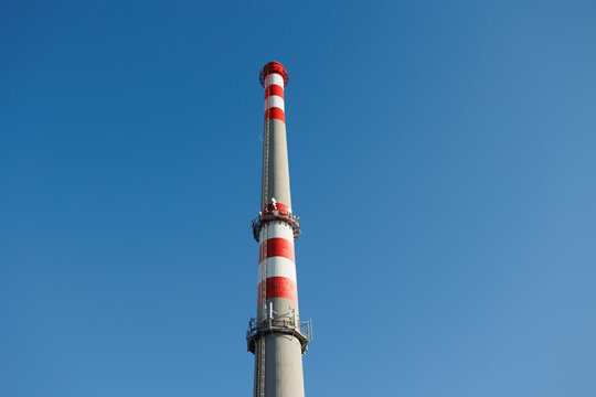 Smokestack and chimney against a clear blue sky. Industrial architecture and building with no smoke, symbolizing zero emissions, reduced pollution, and clean air. Copy space.	