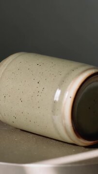 Vertical video: Turntable starting, speckled ceramic cylinder rotating on turntable, showing base