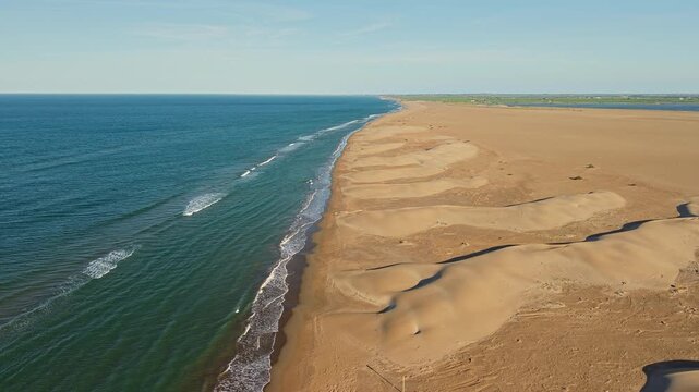 Aerial drone view gliding above untouched coastal sand dunes and turquoise Mediterranean shoreline in the Ebro Delta, Spain.