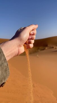 Hand holding fine desert sand in Erg Chebbi Morocco, Sahara travel, tactile nature experience, desert landscape, arid environment, adventure tourism, time running