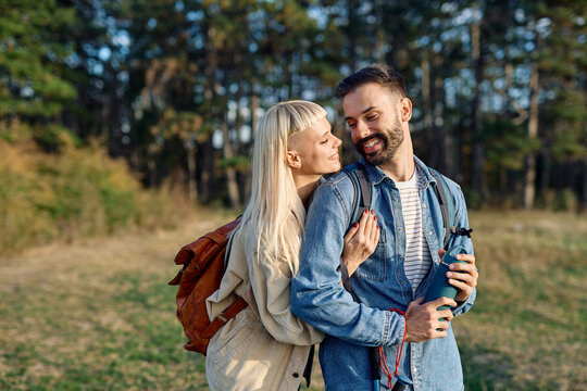 Hiking couple  enjoys nature  taking a break with water bottle  in a lush forest during a sunny day