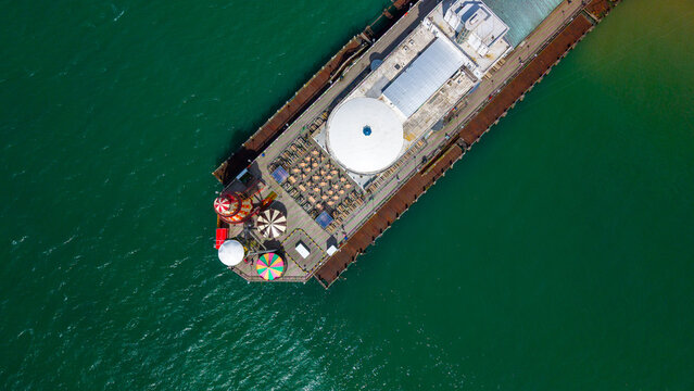 Aerial view of Bournemouth Pier extending into turquoise waters with outdoor seating and colorful amusement rides on the deck in Bournemouth, England, United Kingdom.