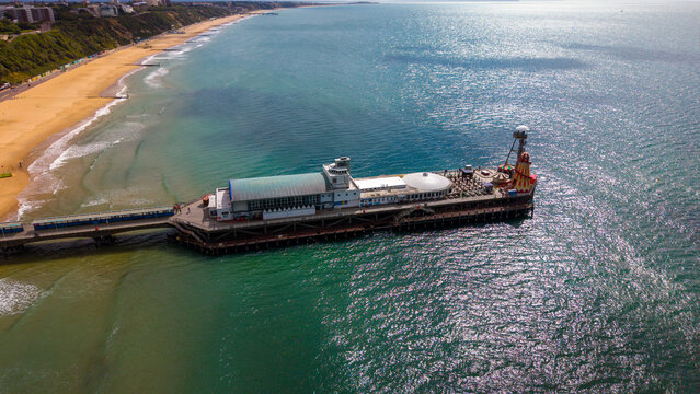 Aerial view of Bournemouth Pier extending into the sparkling sea with the sandy coastline and beach visible in Bournemouth, England, United Kingdom.
