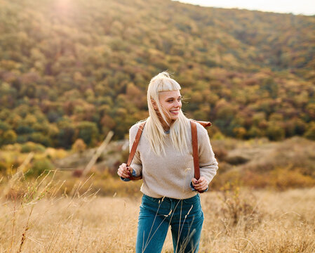 Hiking woman enjoys nature with trekking backpack in a lush forest during a sunny day