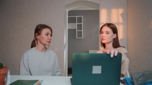 Caucasian tutor and student at home calm grammar coaching session at kitchen table laptop open notebooks and potted plant soft evening light attentive tutor explaining grammar rules while student