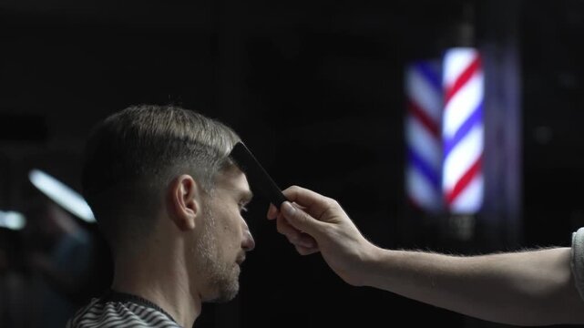 Professional barber carefully checking customer's hair texture and head contours, preparing for precise haircut, vintage barbershop interior with iconic striped pole visible