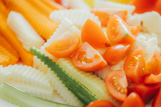 Colorful assortment of sliced vegetables including tomatoes, cucumbers, and carrots arranged on a white plate, showcasing fresh and healthy food presentation