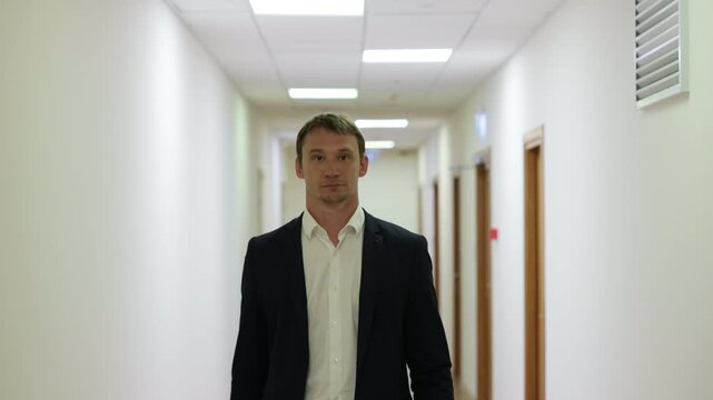 Successful male executive in a formal suit walking through a bright corporate hallway directly towards the camera.Split screen or sequence of a professional businessman walking back and forth in a con