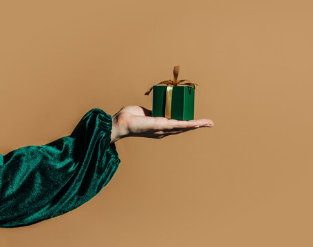 Hand present bright green gift box with golden ribbon
