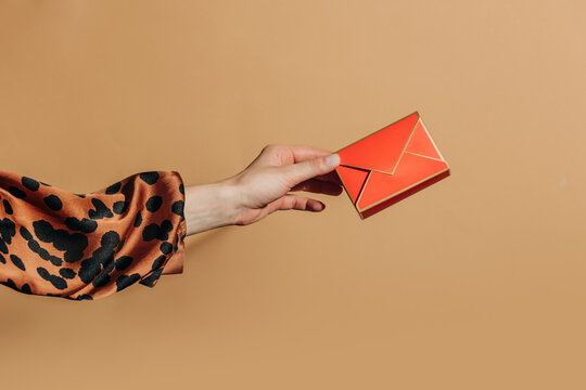 Hand holding bright gift envelope against beige background