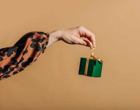 Hand hold green gift box with gold ribbon