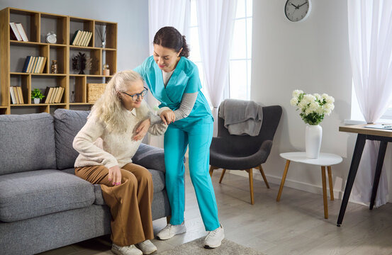 Nurse caregiver supports senior woman mobility. Healthcare worker helps elderly patient stand at home, offering assistance and balance support. Clear homecare support and mobility concept.