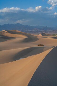 Beautiful vertical view of sand dunes and mountains under a cloudy sky in Death Valley