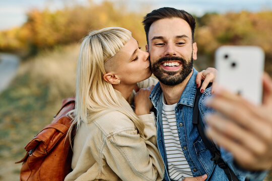 Hiking couple enjoys nature  and takes a selfie photo with a mobile phone  in a lush forest during a sunny day