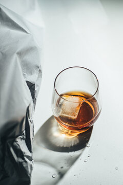 Low key cocktail with ice in a glass beside foil