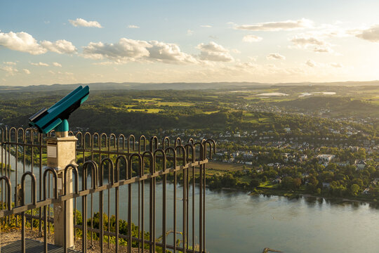 View of a coin-operated telescope overlooking the Rhine river and the rolling green landscape of the Rhine Valley in Konigswinter, North Rhine-Westphalia, Germany.
