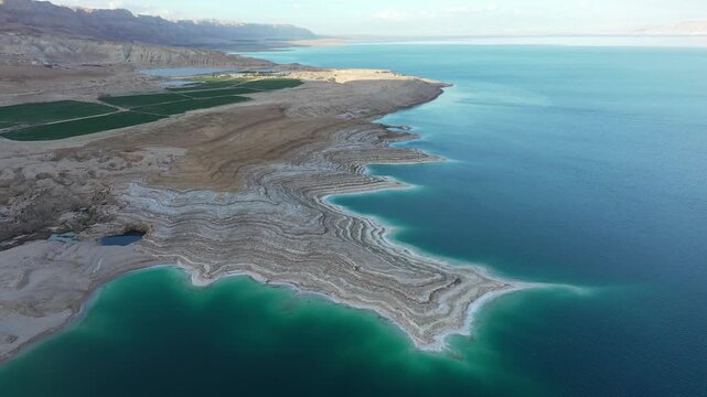 Aerial view of the Dead Sea sinkholes and beach with turquoise water and salt formations in Beersheba, South District, Israel.