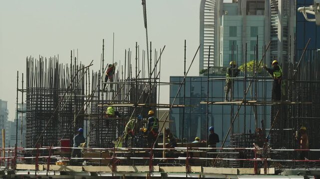Workers at construction site doing rebar tying. Construction process. Skyscraper building process.