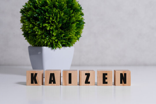 Kaizen improvement sign made of blocks on a wooden desk in a bright room