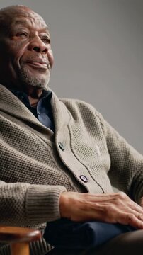Vertical video: Placing hands above navy cloth, man in beige cardigan smoothing, resting in studio