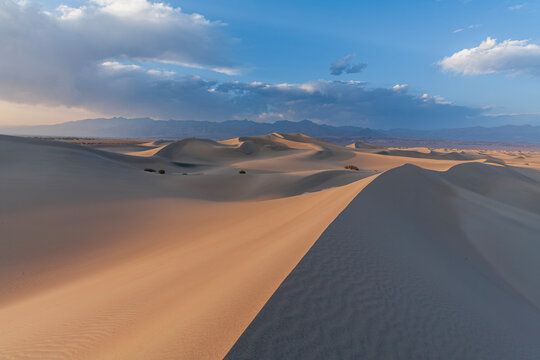Beautiful wide panoramic view of sand dunes and mountains under a cloudy sky in Death Valley