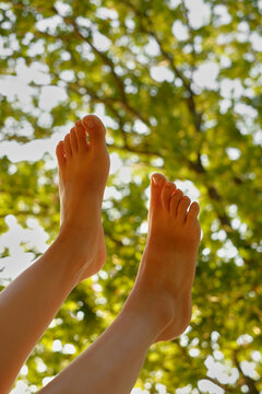 Bare feet raised beneath sunlit forest canopy