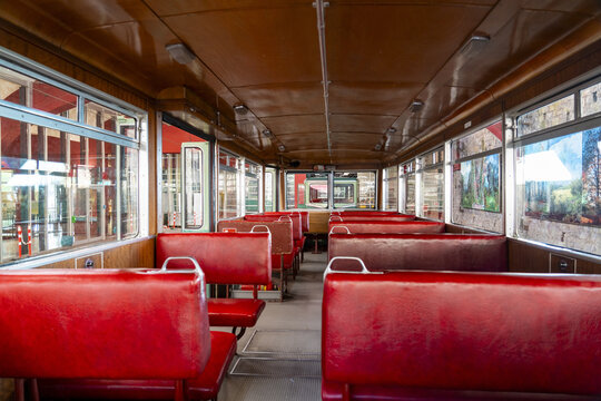 View of the interior of the historic Drachenfelsbahn funicular railway car with red vinyl seats and wooden paneling in Konigswinter, North Rhine-Westphalia, Germany.