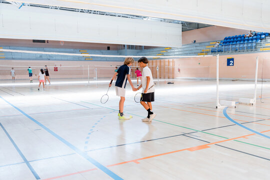 Junior badminton players shake hands after indoor tournament match
