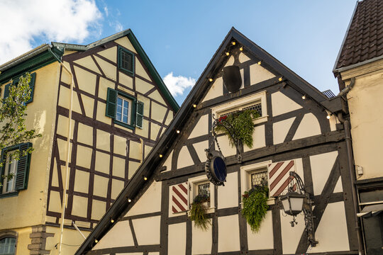 View of traditional half-timbered houses with decorative shutters and hanging flower baskets in the historic town center of Konigswinter, North Rhine-Westphalia, Germany.