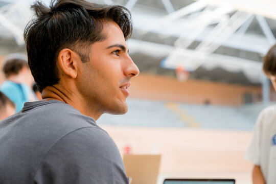 Young man spectator at junior badminton tournament indoors