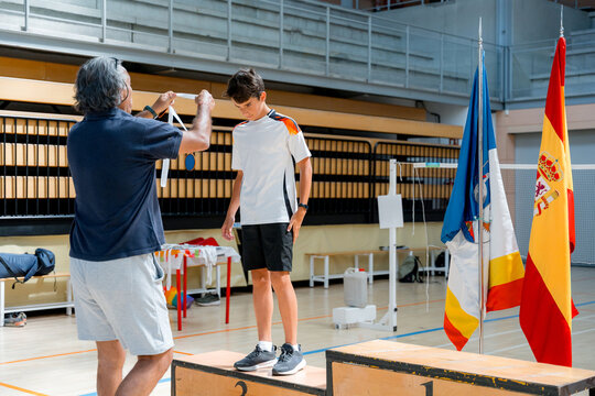 Junior badminton player receive medal at tournament podium