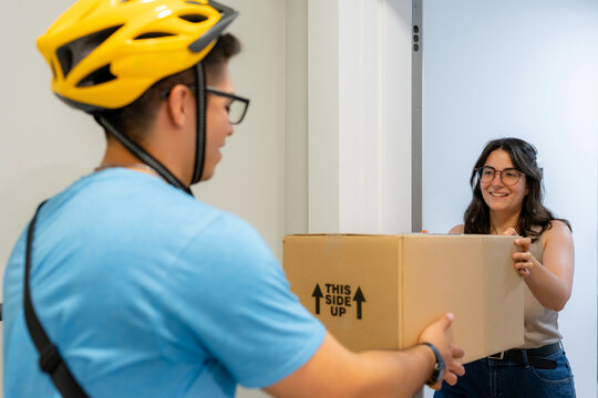 Scooter courier deliver package to smiling customer at door