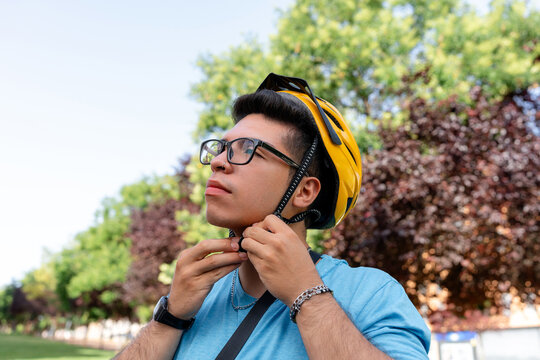 Scooter rider fastening helmet for delivery work outdoors