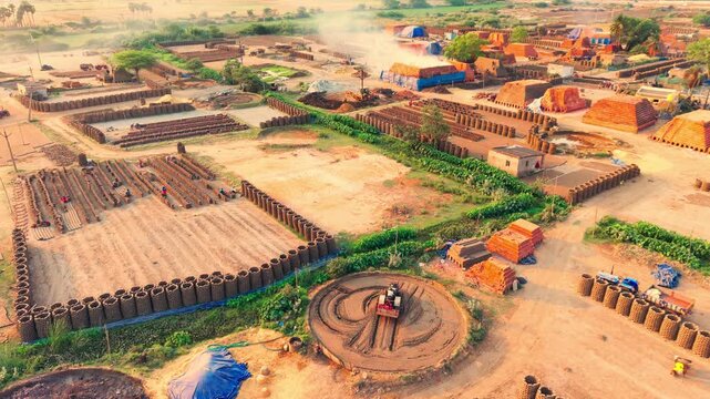 Aerial view of a brick kiln with rows of drying clay bricks and workers in the industrial landscape of Vijayawada, Andhra Pradesh, India.