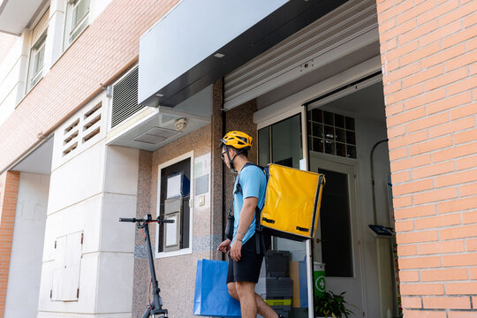 Scooter rider delivering order at urban apartment entrance