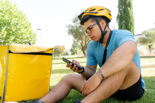 Scooter rider checking smartphone beside delivery bag
