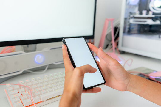 Young woman use smartphone at desktop gaming computer