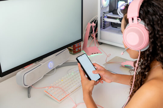 Young woman use smartphone at gaming computer desk