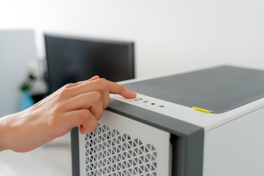 Young woman starting desktop gaming computer at home