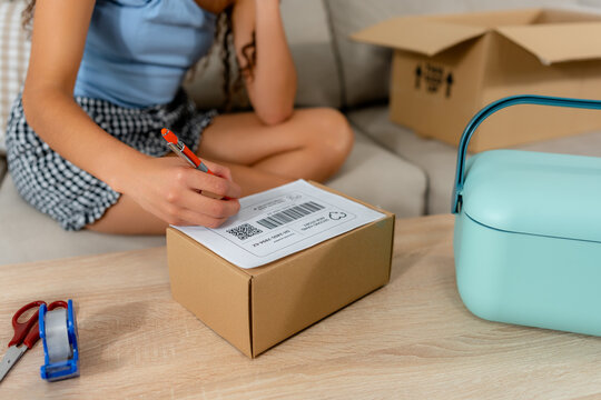Young woman prepare second-hand sale parcel for shipment