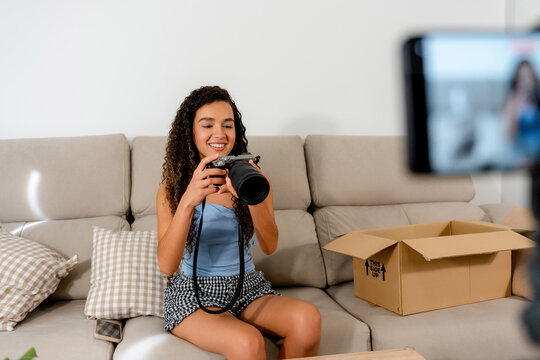 Young woman inspect camera before second-hand item packaging