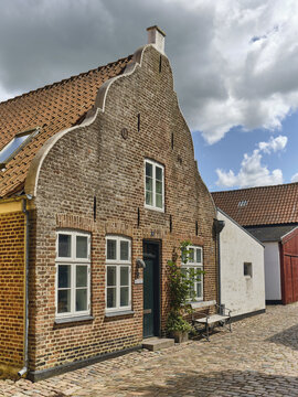 View of a historic brick house with a stepped gable and white window frames on a cobblestone street in the old town of Ribe, Denmark.