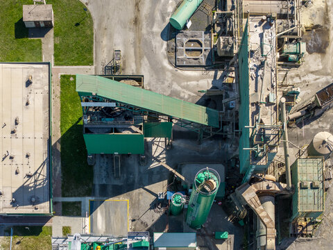 Aerial view of the Masfalt asphalt plant featuring industrial storage silos, a green conveyor belt system, and paved yard areas in Dabrowa Gornicza, Wojewodztwo slaskie, Poland.