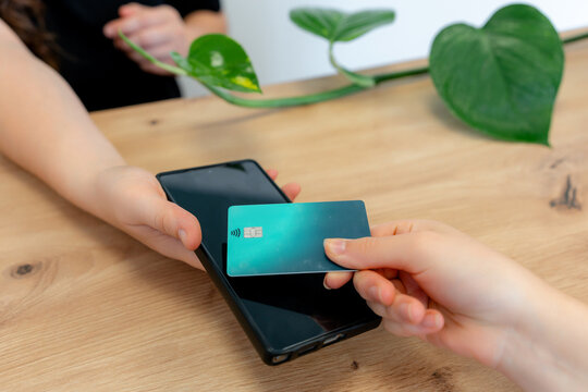 Contactless card payment with smartphone at wooden counter
