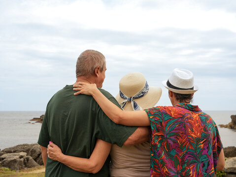 Senior couple and daughter share a seaside family embrace